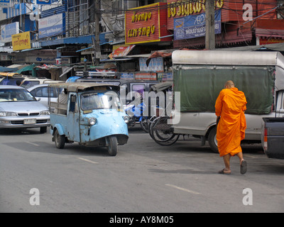 Monk in saffron robes walks towards tuk tuk on busy street Ayutthaya Thailand Stock Photo