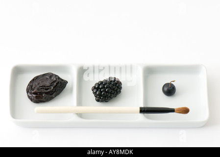Prune, blackberry and blueberry on dish with paintbrush Stock Photo