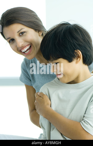 Teenage girl looking over boy's shoulder at camera, both smiling Stock Photo