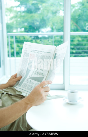 Man reading newspaper at table, cropped view Stock Photo