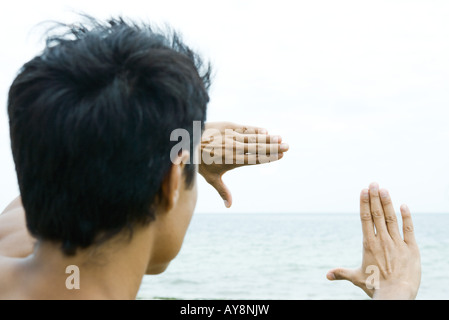 Man by the sea, looking at view through finger frame Stock Photo
