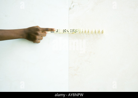 Child knocking over line of dominoes, cropped view of hand Stock Photo