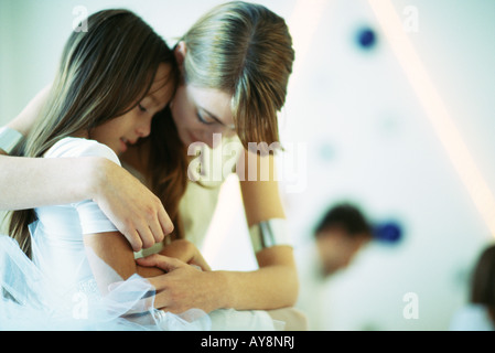 Mother embracing daughter, both looking down, close-up Stock Photo