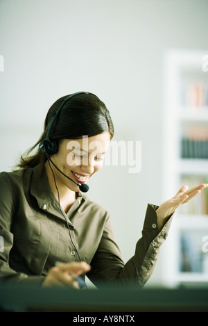 Woman wearing headset, gesturing with hand, looking down Stock Photo