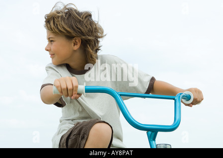 Boy riding bicycle, looking over shoulder, close-up Stock Photo