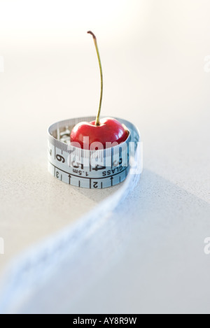 Measuring tape wrapped around cherry, close-up Stock Photo