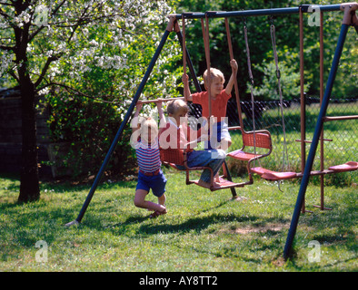 Young children playing on swings in garden Stock Photo