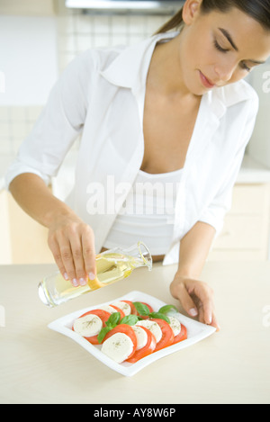 Woman pouring olive oil on antipasto Stock Photo