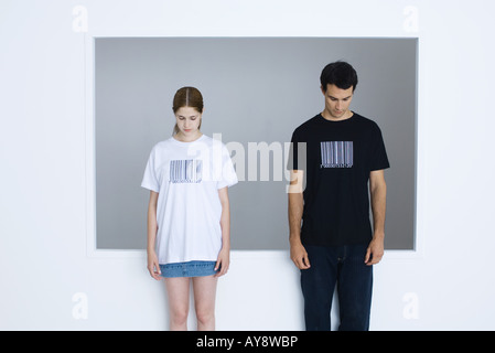 Two young adults wearing tee-shirts printed with bar codes, both looking down Stock Photo