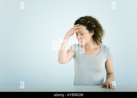 Woman holding head, eyes closed Stock Photo