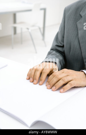 Professional man sitting at desk, reading Braille, cropped view of hands Stock Photo