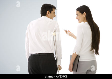 Two office colleagues talking, one using crutches Stock Photo