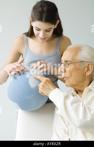 Grandfather and granddaughter looking at globe together
