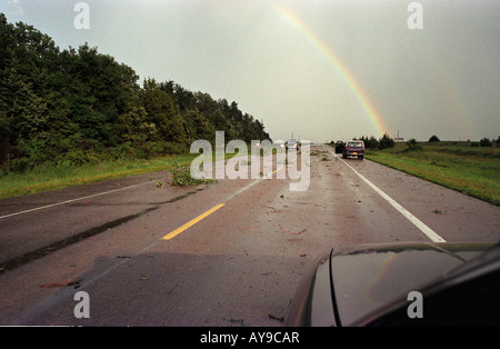Rainbow and residents clearing downed branhes after a tornadic thunderstorm passed near O'Neill, Nebraska, June, 2004. Stock Photo