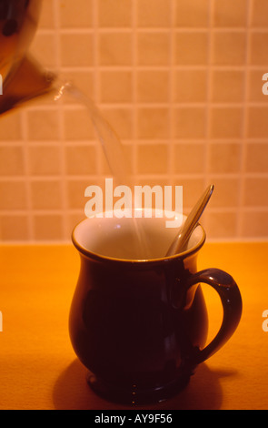 Person pouring boiling water into a mug to make a hot drink Stock Photo