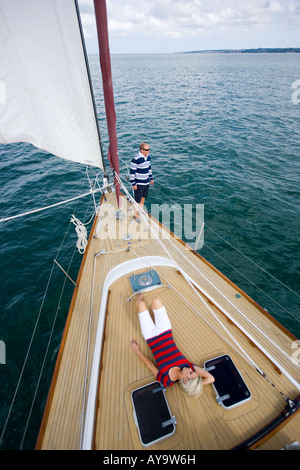 Woman lying on deck of sailing yacht, Cowes, Isle of Wight, UK Stock Photo