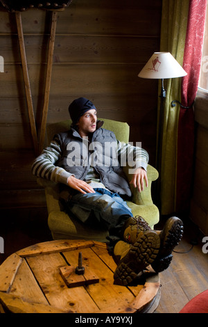 Man sitting on armchair with feet up on table in Apres ski bar, Tignes, France Stock Photo