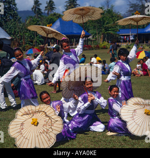 Six female Chinese Fijian dancers in a group posed with pretty white sun brollies dressed in long purple and white satin dresses Stock Photo