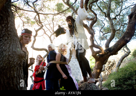 A princess in a purple gown and a navy officer held captive by armed pirates Stock Photo