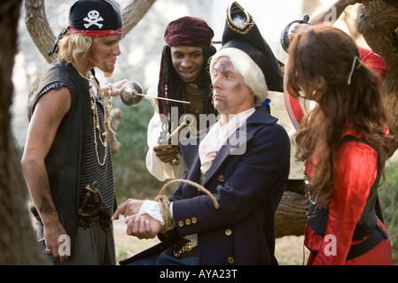 View of armed pirates holding a navy officer captive and threatening him with a sword and a gun Stock Photo