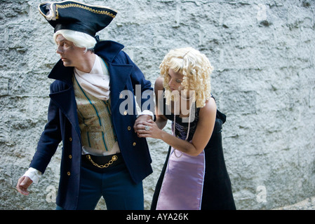 View of a navy officer and a princess sneaking around a castle wall Stock Photo