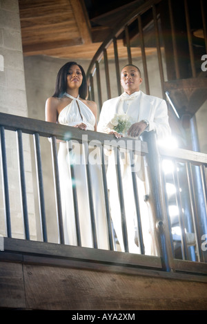 Young bride and groom looking down over balcony railing Stock Photo