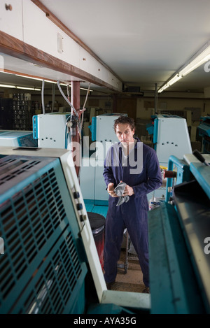 Portrait of a man in coveralls behind a printing machine Stock Photo