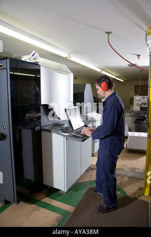 View of a man in coveralls operating a machine by using a computer Stock Photo