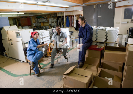 View of two men and a woman enjoying a coffee break while working in a warehouse Stock Photo