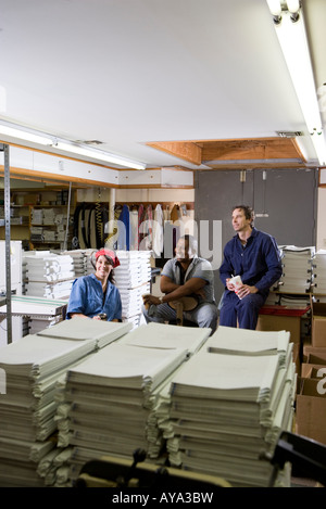 View of two men and a woman enjoying a coffee break while working in a warehouse Stock Photo