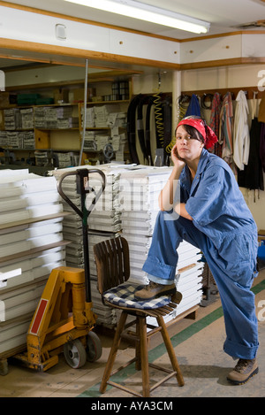Portrait of a woman standing next to a stool in a warehouse Stock Photo