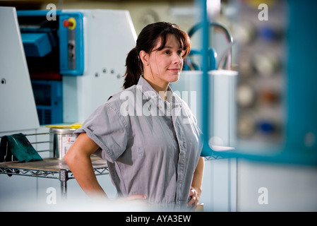 View of a woman in coveralls standing in front of some machinery Stock Photo