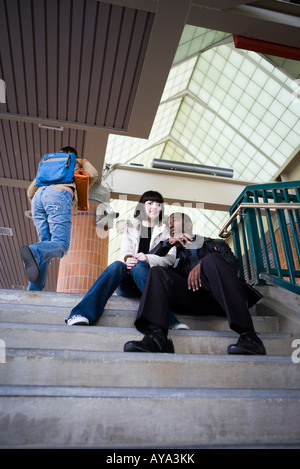 Young inter-racial couple sitting at the top of a flight of stairs at a public train station Stock Photo