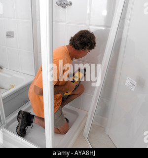 Plumber Using Power Drill Fixing Shower Panel in New Bathroom Stock Photo
