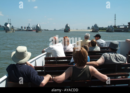 Back view of passengers on tour boat trip to River Thames flood barrier one gate closed for routine testing Silvertown (left) New Charlton London UK Stock Photo