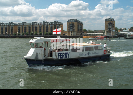 East London River Thames small ferry running between Hilton hotel on South shore to Canary Wharf redevelopment area opposite Stock Photo