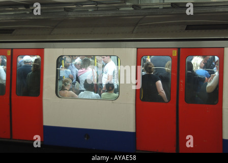 View through carriage windows standing room only in London Transport underground train crowded with evening rush hour commuters England UK Stock Photo