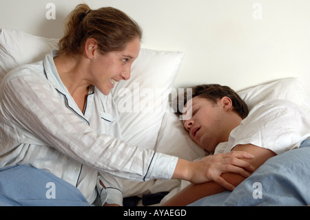 Angry young woman shakes her snoring husband Stock Photo