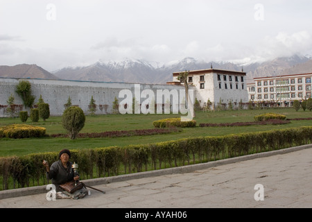 Tibetan pilgrim on the sidewalk in front of the Potala Palace in Tibet Stock Photo