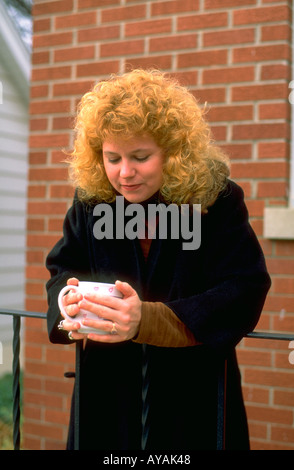 Woman age 27 holding morning coffee in the cool autumn. Western Springs Illinois USA Stock Photo