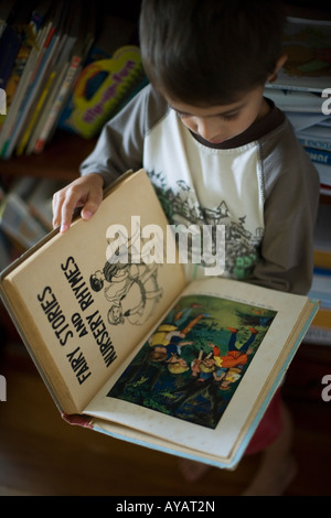 Boy aged six years reads book of Fairy Tales and Nursery Rhymes Stock Photo