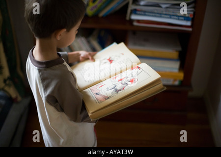 Boy aged six years reads book of Fairy Tales and Nursery Rhymes Stock Photo