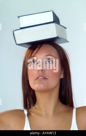 Young woman balancing books on head, studio Stock Photo