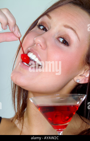 Portrait of young woman eating cherry from cocktail Stock Photo