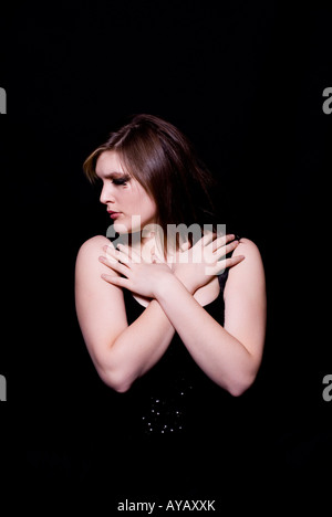 Woman hands on chest looking away against a black background Stock Photo