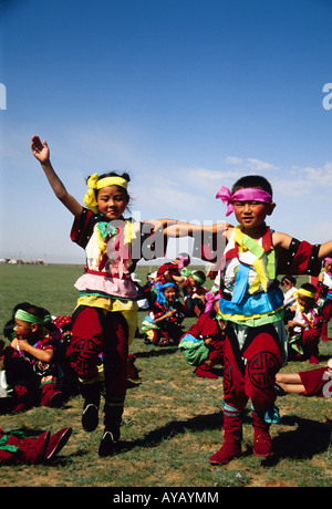 Costumed Mongolian children dancing at Nadam Summer Festival on grasslands of Siziwang Banner near Hohhot in Inner Mongolia Stock Photo