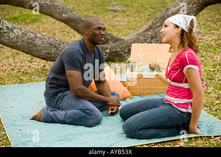 Young couple conversing while sitting on a picnic blanket Stock Photo
