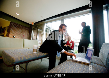 Businessman on cell phone while his colleagues have coffee in the background Stock Photo