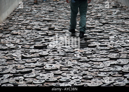 A visitor walks across the Shalechet - Fallen Leaves exhibit, in the Memory Zone of the Jüdisches (Jewish) Museum, Berlin. Stock Photo