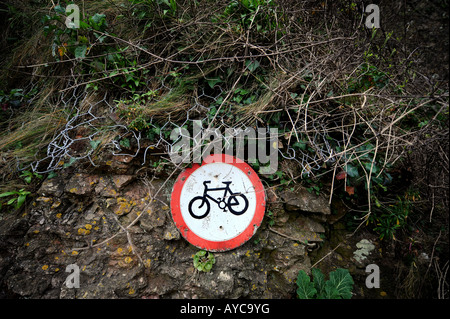 A forlorn and battered No Cycling sign adorns a cliff wall in Tenby, as vine an weeds start to encroach upon it Stock Photo